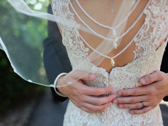 Hands holding a woman’s back who is wearing a veil