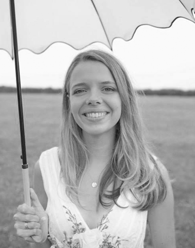 Black and white image of a woman smiling holding an umbrella