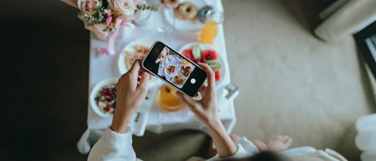 Hotel Guest taking a photo of her complimentary breakfast in her room 